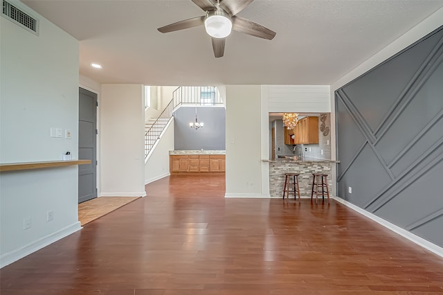 unfurnished living room with hardwood / wood-style flooring, sink, and ceiling fan with notable chandelier