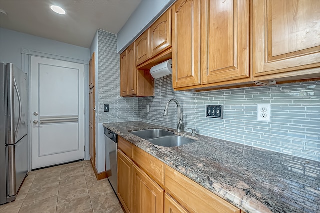 kitchen featuring sink, appliances with stainless steel finishes, tasteful backsplash, and dark stone countertops