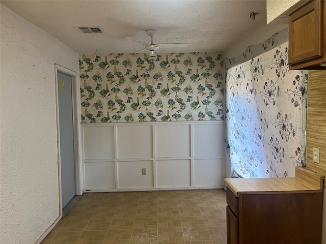 empty room with ceiling fan and a textured ceiling