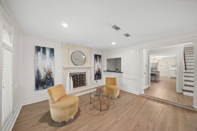 living area featuring a large fireplace, crown molding, and hardwood / wood-style floors