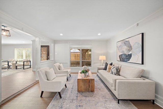 living room with ornamental molding, plenty of natural light, ornate columns, and light hardwood / wood-style flooring