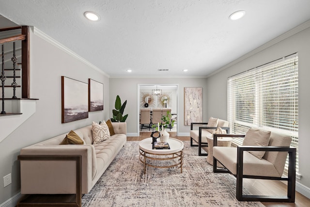 living room featuring crown molding, a chandelier, wood-type flooring, and a textured ceiling