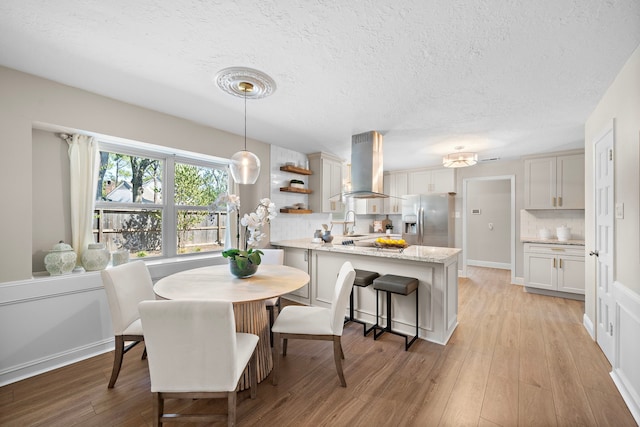 dining room featuring sink, light hardwood / wood-style floors, and a textured ceiling