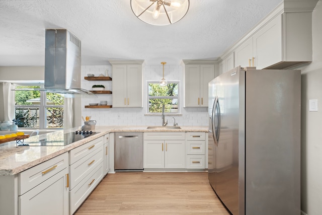 kitchen featuring light stone counters, sink, island exhaust hood, light hardwood / wood-style flooring, and appliances with stainless steel finishes