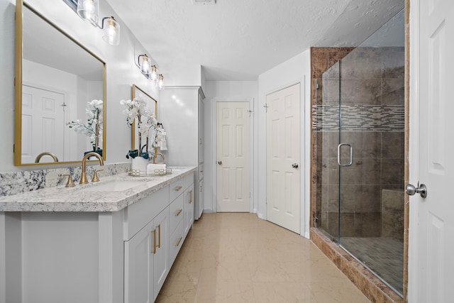 bathroom featuring vanity, a textured ceiling, and a shower with door