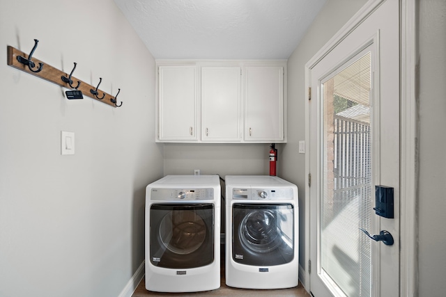 washroom featuring a textured ceiling, separate washer and dryer, and cabinets