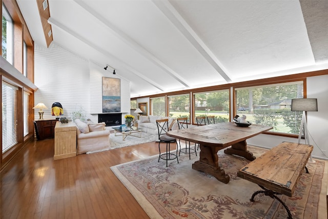 dining space featuring wood-type flooring, lofted ceiling with beams, and a wealth of natural light