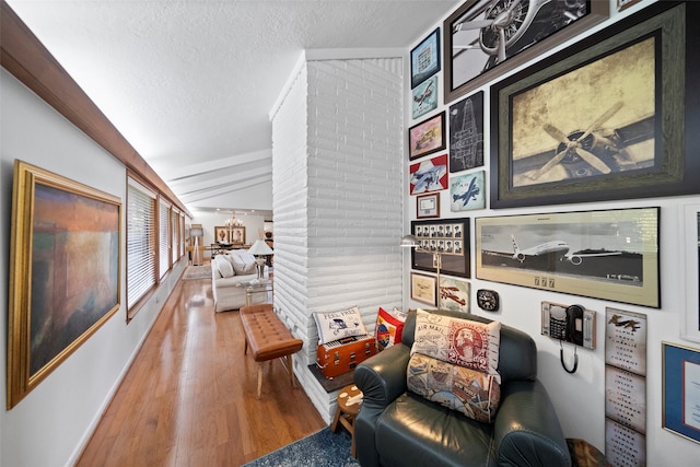 living area with lofted ceiling, hardwood / wood-style flooring, and a textured ceiling