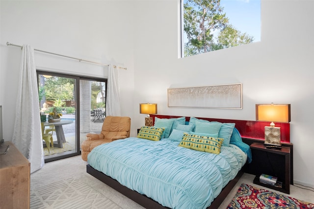 bedroom with light colored carpet, a towering ceiling, and access to exterior