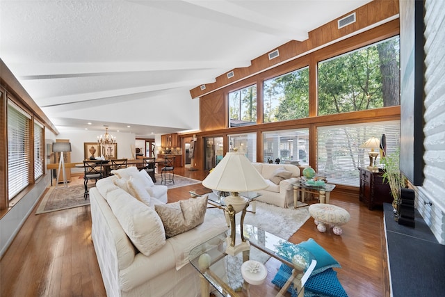 living room featuring an inviting chandelier, beamed ceiling, dark hardwood / wood-style floors, and high vaulted ceiling