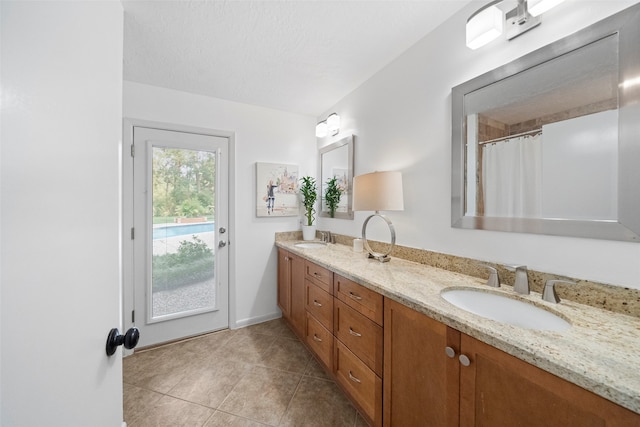 bathroom featuring tile patterned flooring, vanity, and a textured ceiling