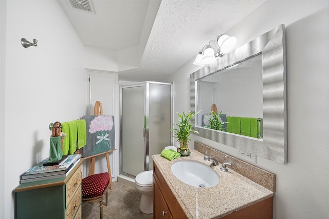 bathroom with a textured ceiling, walk in shower, vanity, and toilet