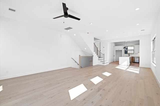 unfurnished living room with ceiling fan, light wood-type flooring, and sink