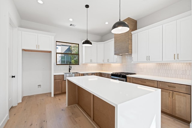 kitchen with white cabinetry, black gas range oven, and a kitchen island