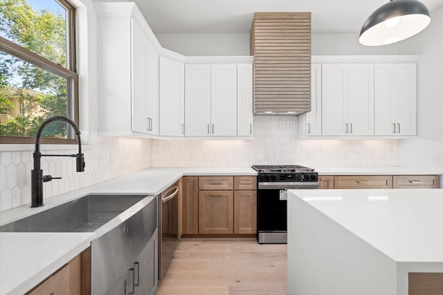 kitchen with light wood-type flooring, sink, stainless steel appliances, and white cabinetry