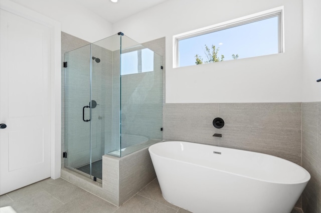 bathroom with shower with separate bathtub, tile patterned floors, and tile walls