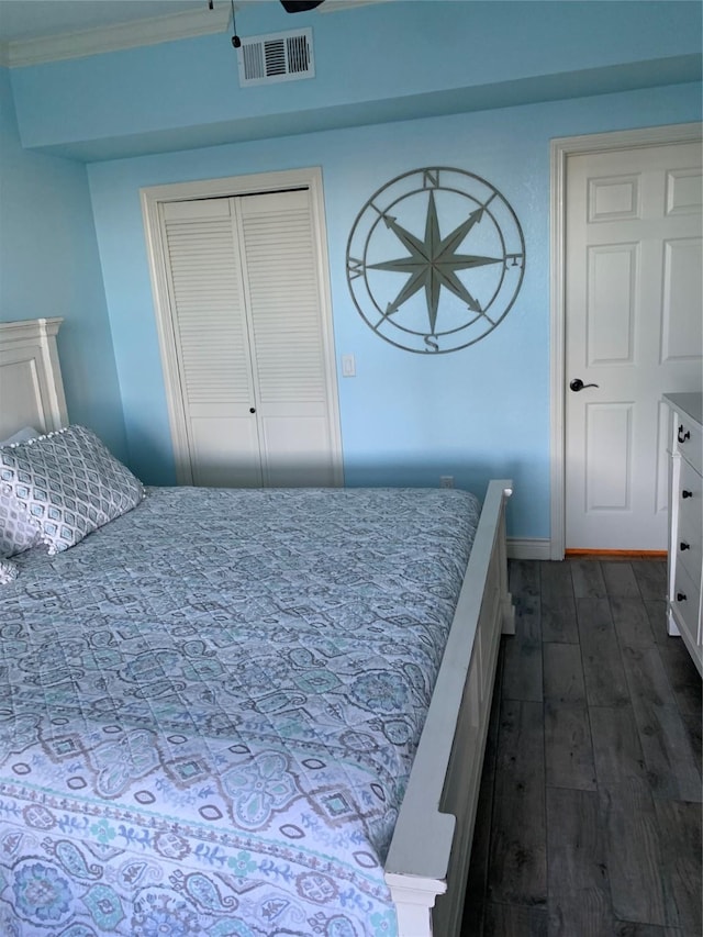 bedroom featuring a closet, ornamental molding, and dark wood-type flooring