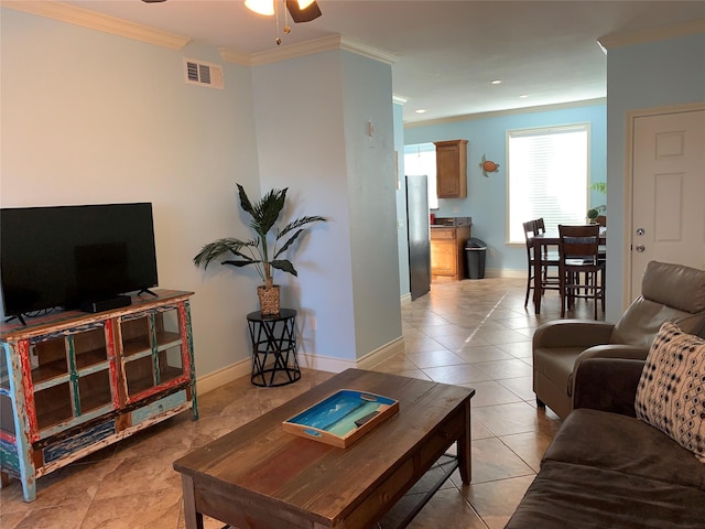 tiled living room with ceiling fan and crown molding