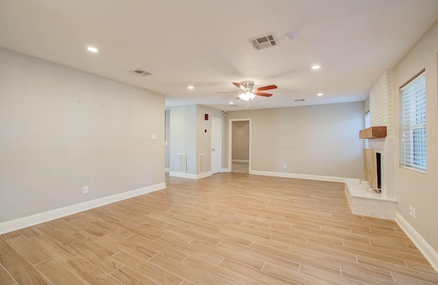 empty room featuring a large fireplace and ceiling fan