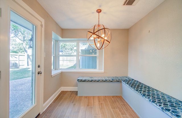 unfurnished dining area featuring a healthy amount of sunlight, light hardwood / wood-style flooring, and a chandelier