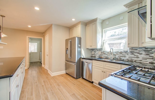 kitchen featuring backsplash, sink, light hardwood / wood-style flooring, decorative light fixtures, and stainless steel appliances