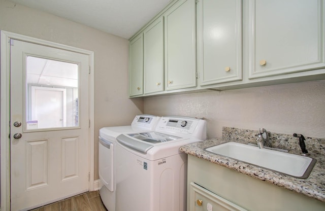 laundry area featuring washer and clothes dryer, cabinets, sink, and hardwood / wood-style flooring