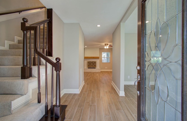 foyer featuring ceiling fan, a large fireplace, and light hardwood / wood-style floors