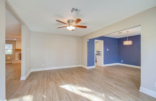 unfurnished room featuring a fireplace, light hardwood / wood-style floors, and ceiling fan