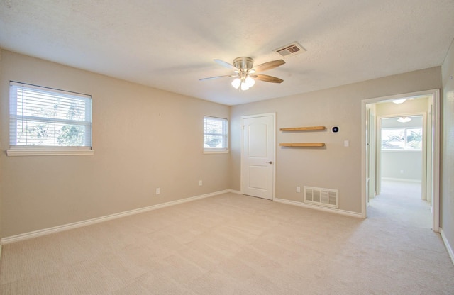 carpeted spare room featuring ceiling fan and a textured ceiling