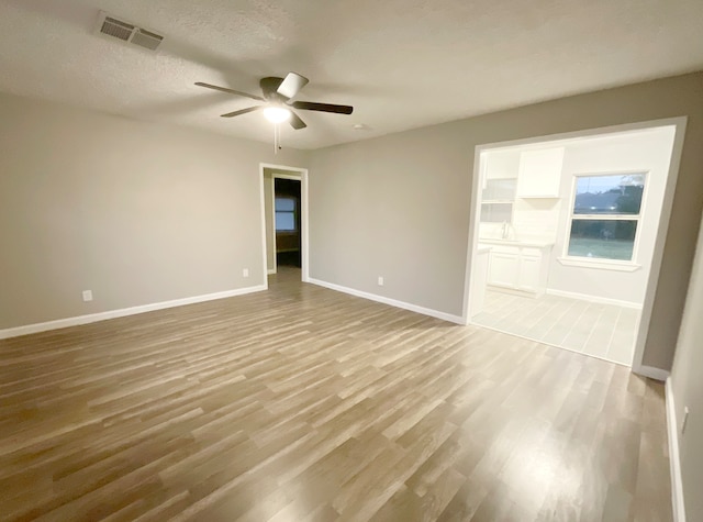 unfurnished room with a textured ceiling, light hardwood / wood-style floors, and ceiling fan