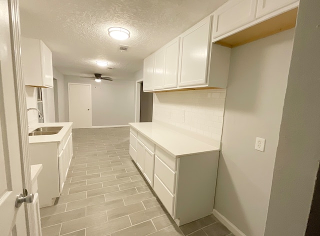 kitchen featuring decorative backsplash, white cabinets, ceiling fan, a textured ceiling, and sink