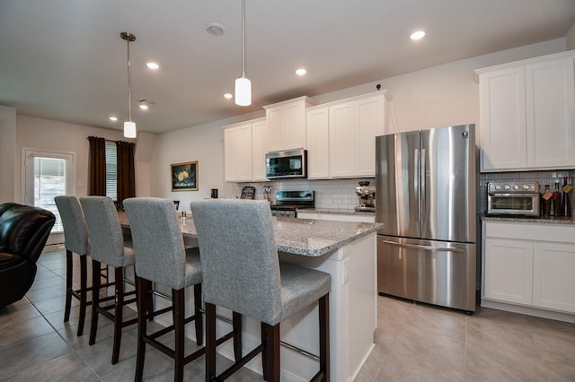 kitchen with stainless steel appliances, a kitchen bar, and white cabinets