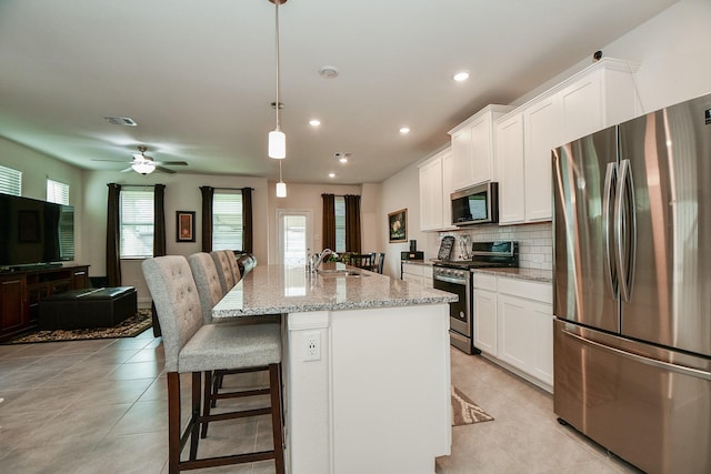 kitchen with a breakfast bar, visible vents, white cabinetry, appliances with stainless steel finishes, and decorative backsplash