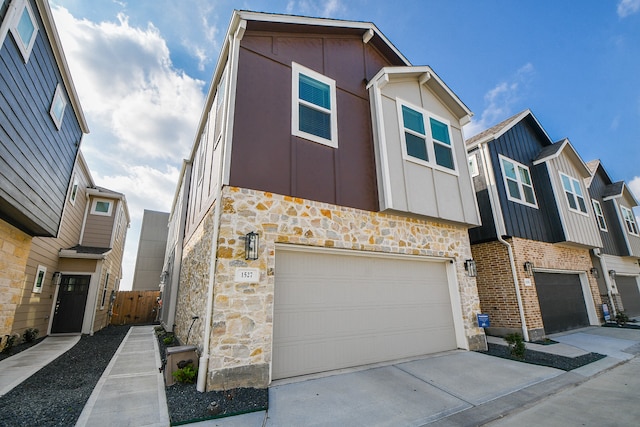 townhome / multi-family property featuring stone siding, concrete driveway, board and batten siding, and an attached garage