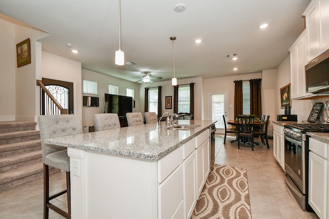 kitchen featuring visible vents, a breakfast bar area, appliances with stainless steel finishes, white cabinetry, and a sink