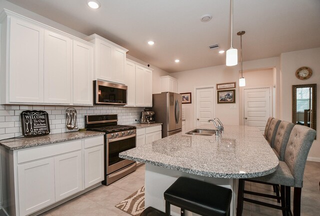 kitchen featuring appliances with stainless steel finishes, sink, a kitchen breakfast bar, and white cabinetry