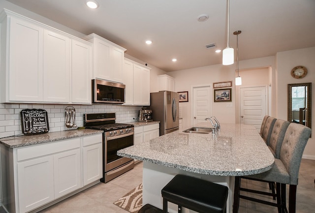 kitchen with tasteful backsplash, white cabinetry, stainless steel appliances, and a sink