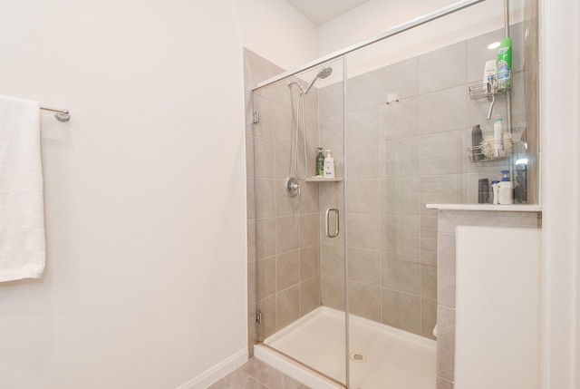 full bath featuring a shower stall and baseboards