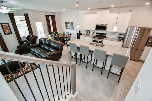 kitchen with light stone counters, a breakfast bar area, stainless steel appliances, backsplash, and a sink