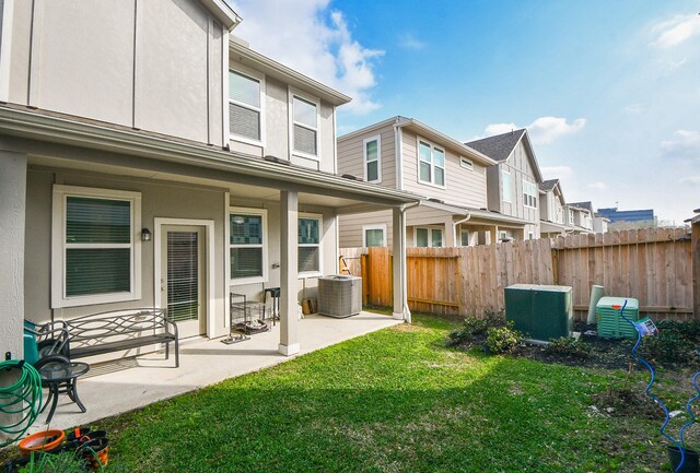 back of property featuring a yard, cooling unit, and a patio