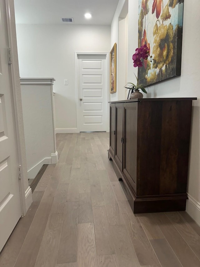 hall featuring visible vents, light wood-style flooring, and baseboards