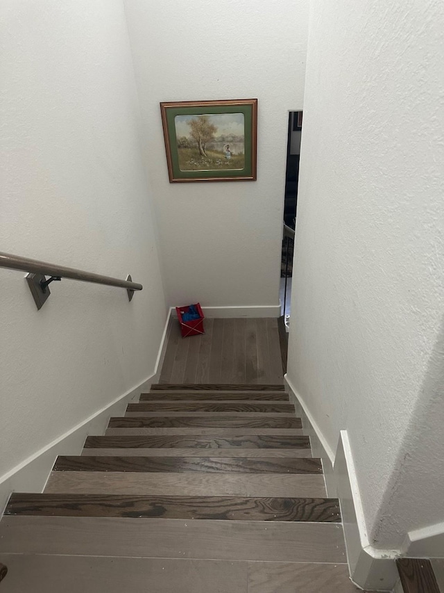 staircase with baseboards and wood finished floors