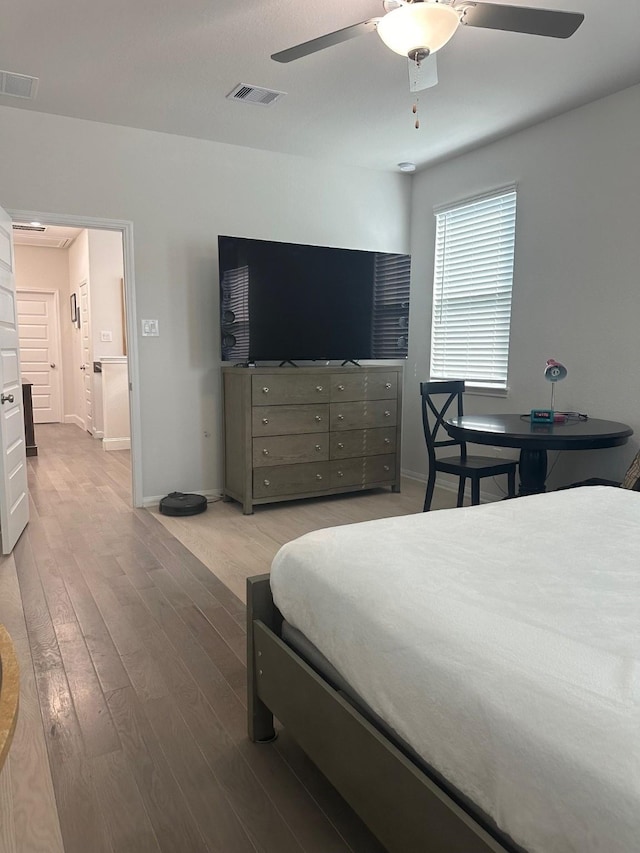 bedroom featuring ceiling fan, wood finished floors, visible vents, and baseboards