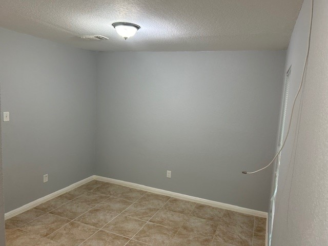 unfurnished room with light tile patterned flooring and a textured ceiling