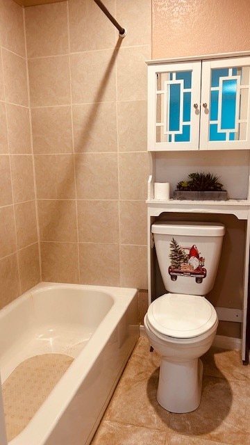 bathroom with tile patterned flooring, toilet, and tiled shower / bath combo