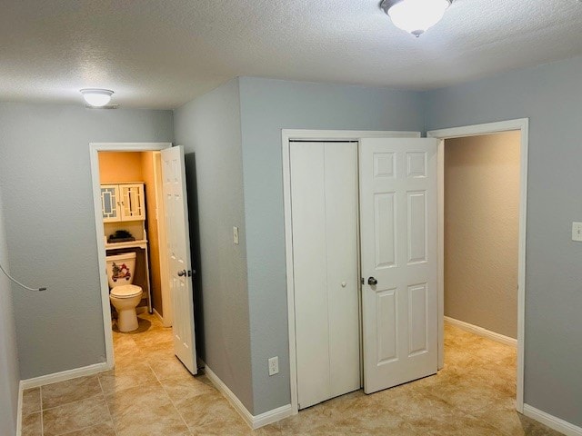 bedroom featuring a closet, ensuite bathroom, and a textured ceiling