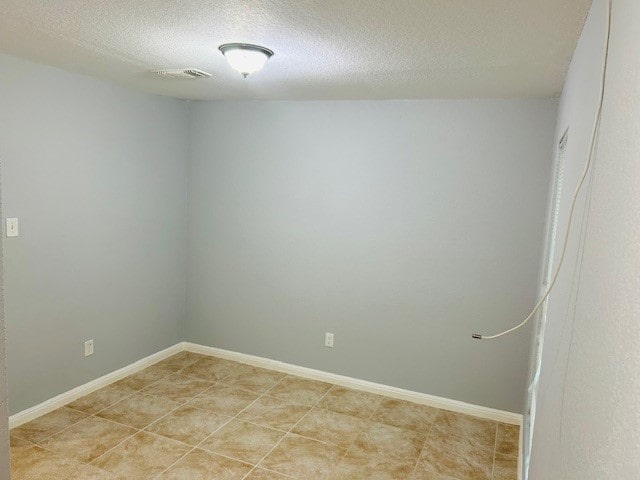 spare room featuring a textured ceiling and light tile patterned flooring