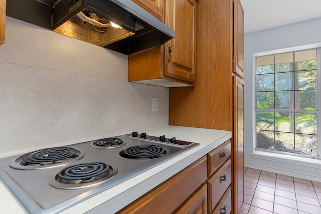 kitchen with light tile patterned flooring, stainless steel electric cooktop, and range hood