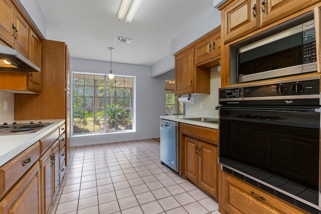 kitchen with light tile patterned flooring, hanging light fixtures, appliances with stainless steel finishes, and sink