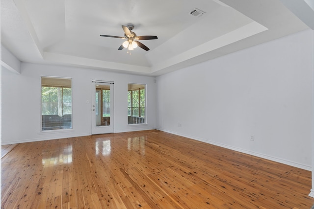 spare room featuring a tray ceiling, hardwood / wood-style flooring, and ceiling fan